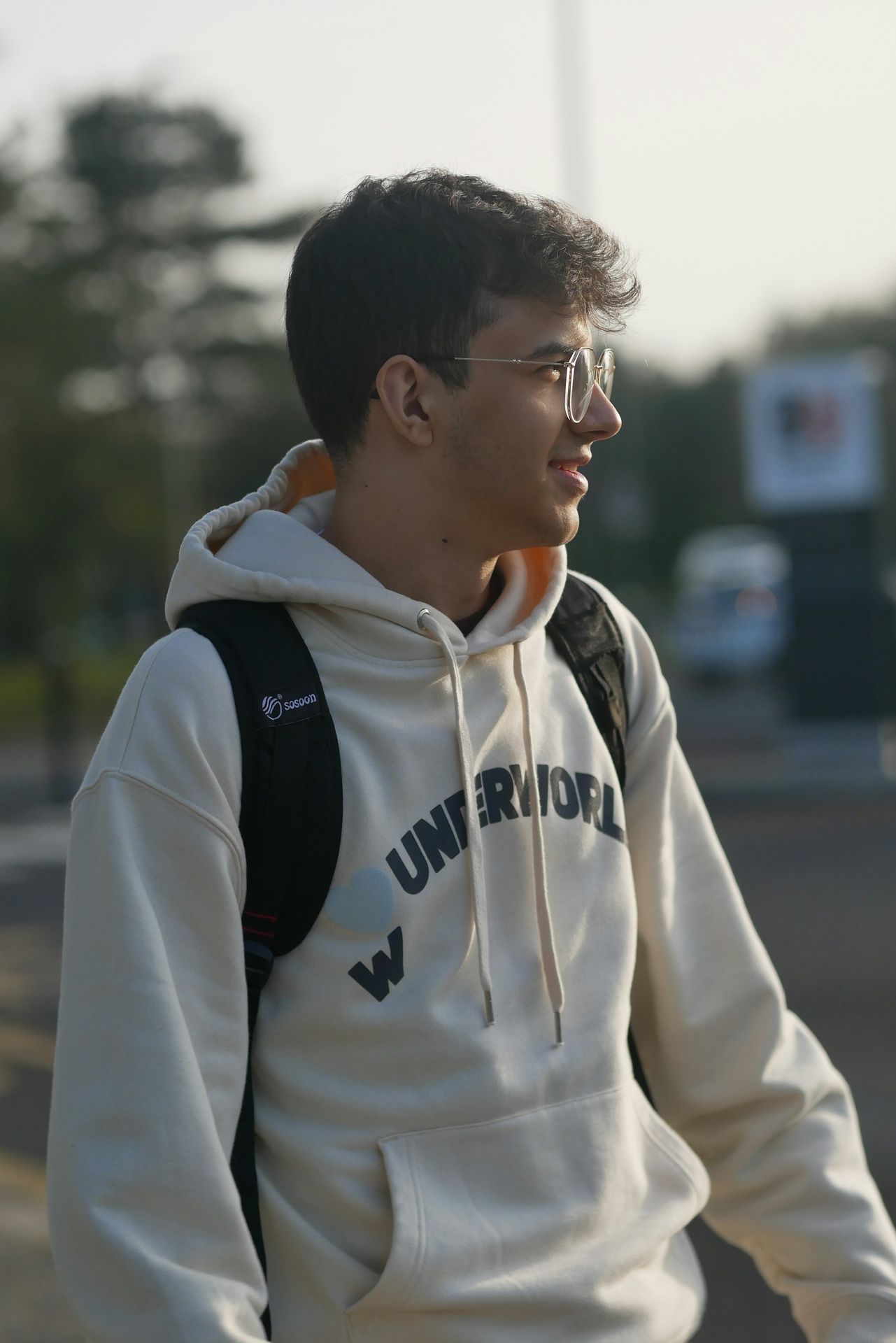 a young man wearing a white sweatshirt and black backpack